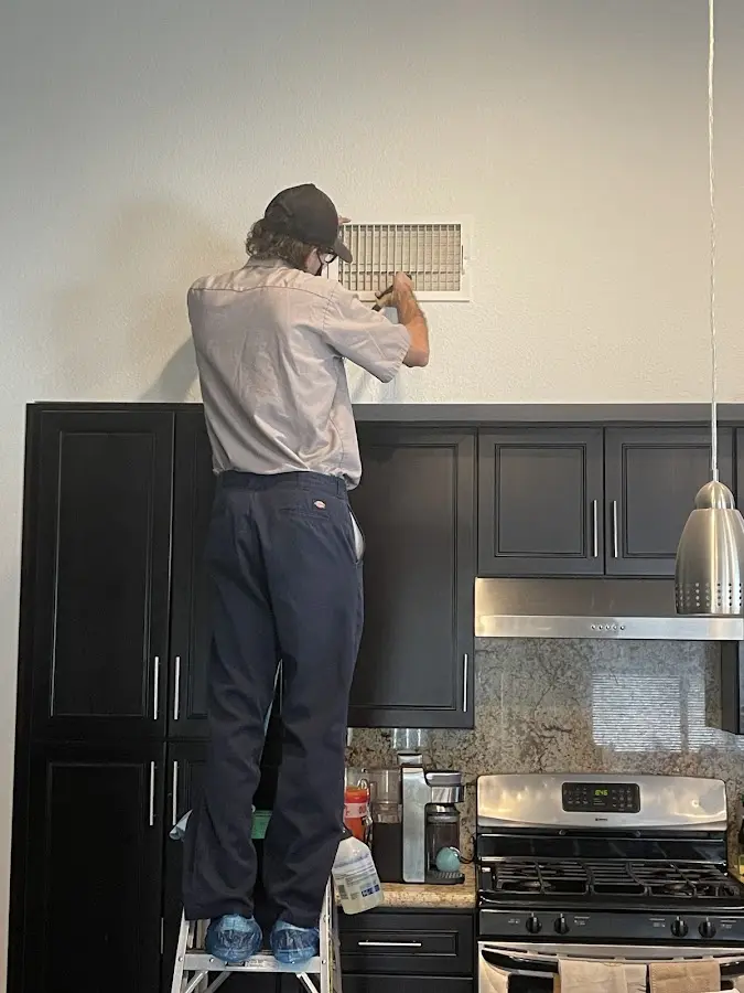 Technician inspecting an air vent during HVAC service in Green Bay